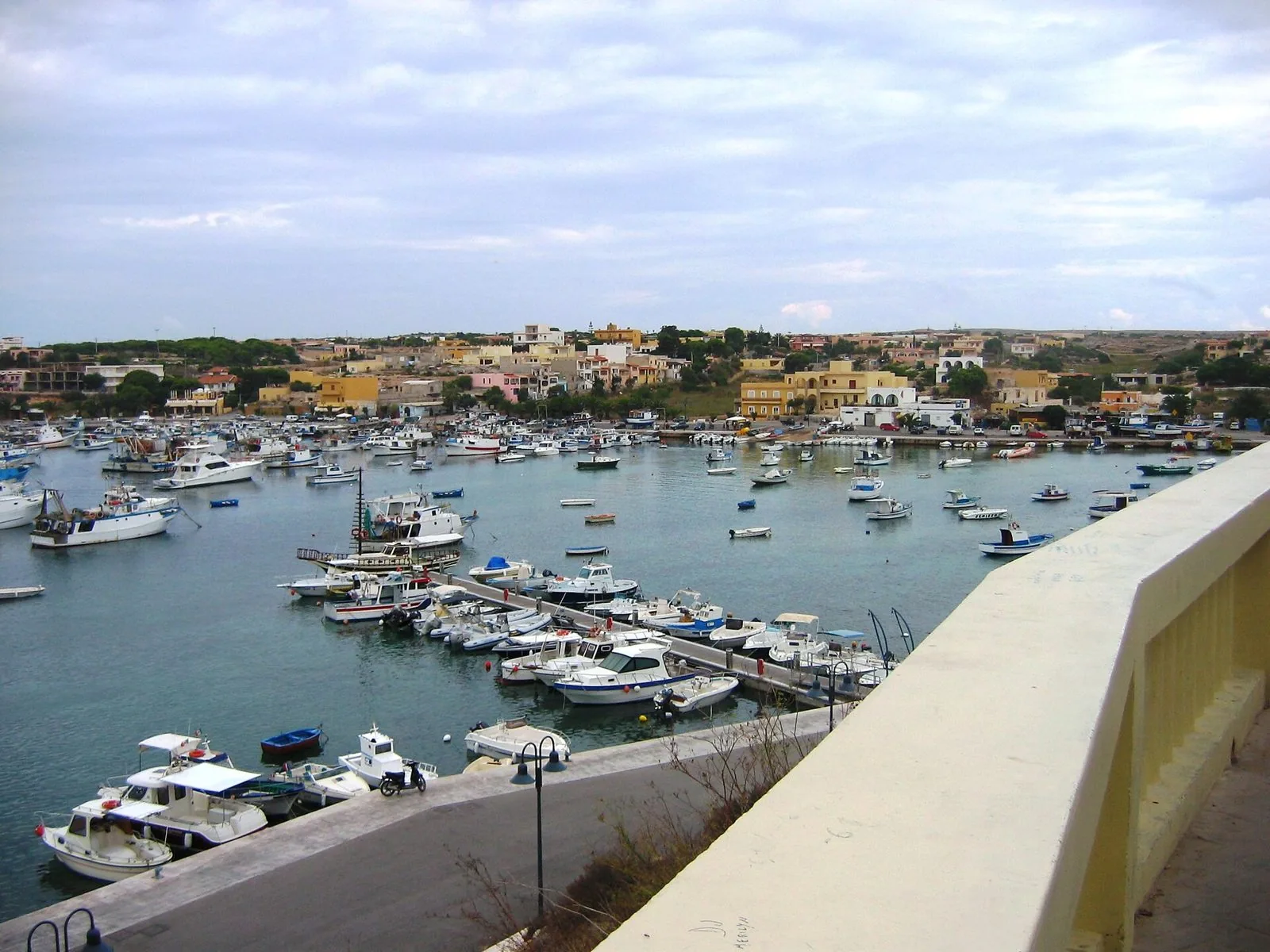 Il Porto Vecchio di Lampedusa visto dall'alto, con le barche ormeggiate e le case del paese sullo sfondo