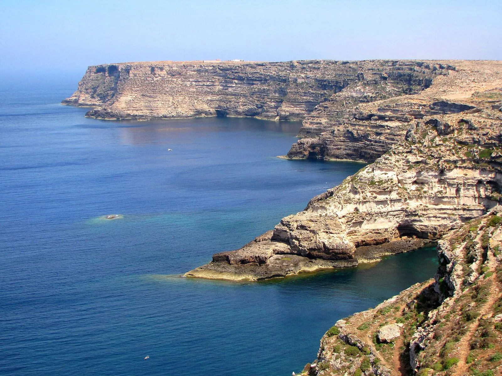 Falesie calcaree a picco sul mare blu lungo la costa di Lampedusa