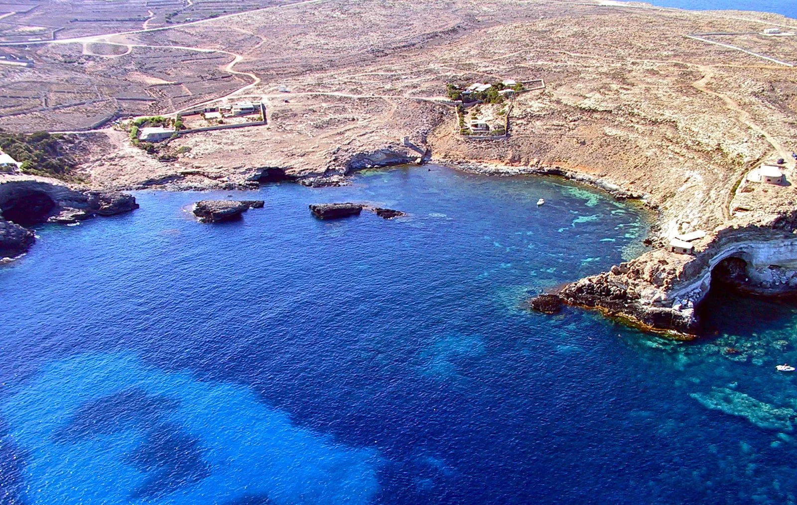 Veduta aerea del Mare Morto a Lampedusa, con acqua blu trasparente e fondali rocciosi visibili sotto la superficie
